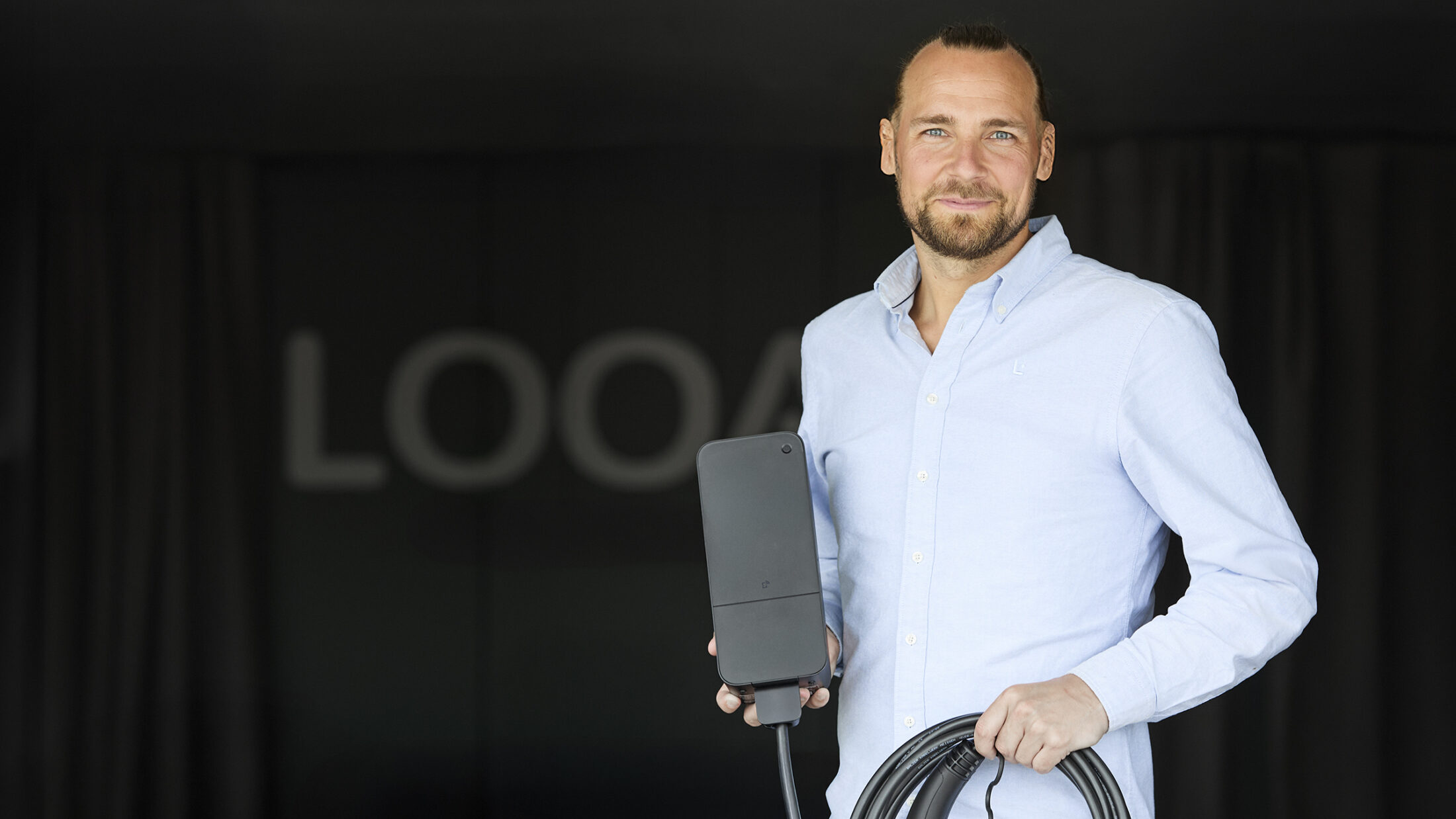 Søren Behnfeld CEO at Looad holding an Amina C EV charger, demonstrating compact portable design for charge point operator partner deployment