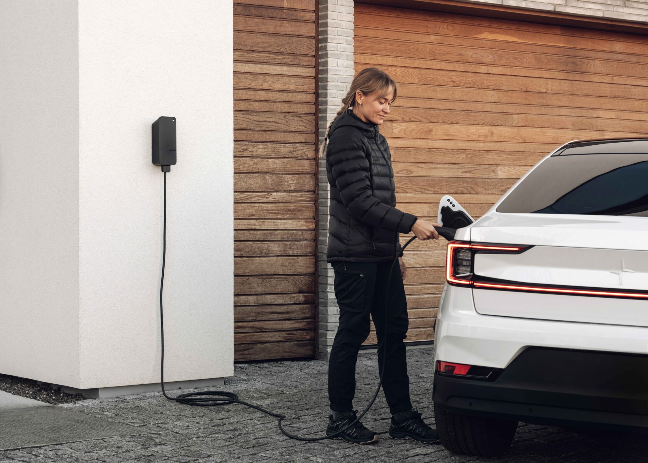 Aufladen eines Elektroautos neben einer Betonmauer mithilfe einer „White-Label“-Ladestation von amina mit VERDO-Branding – ein Beispiel für maßgeschneiderte Ladelösungen für Privathaushalte für Energiepartner.