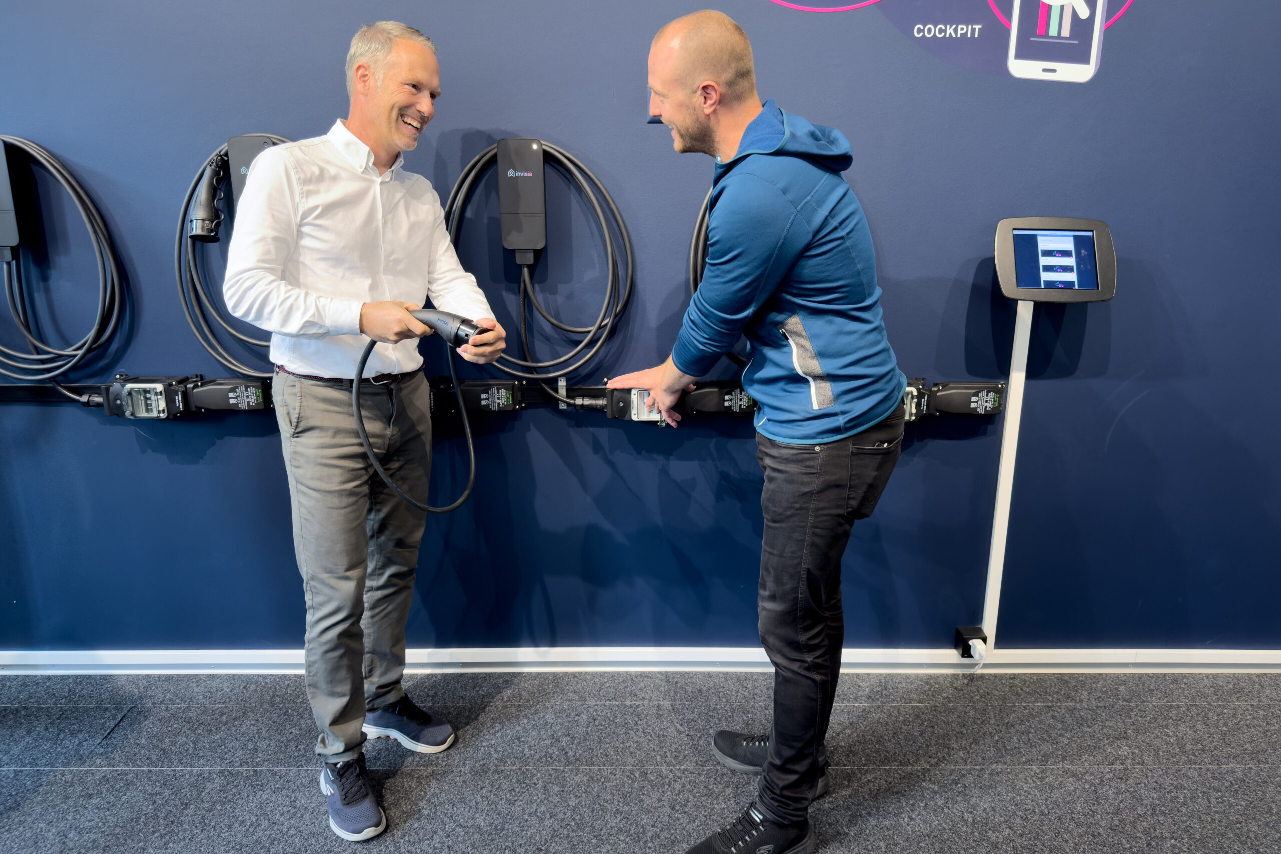 Two technicians examining amina EV chargers at exhibition display