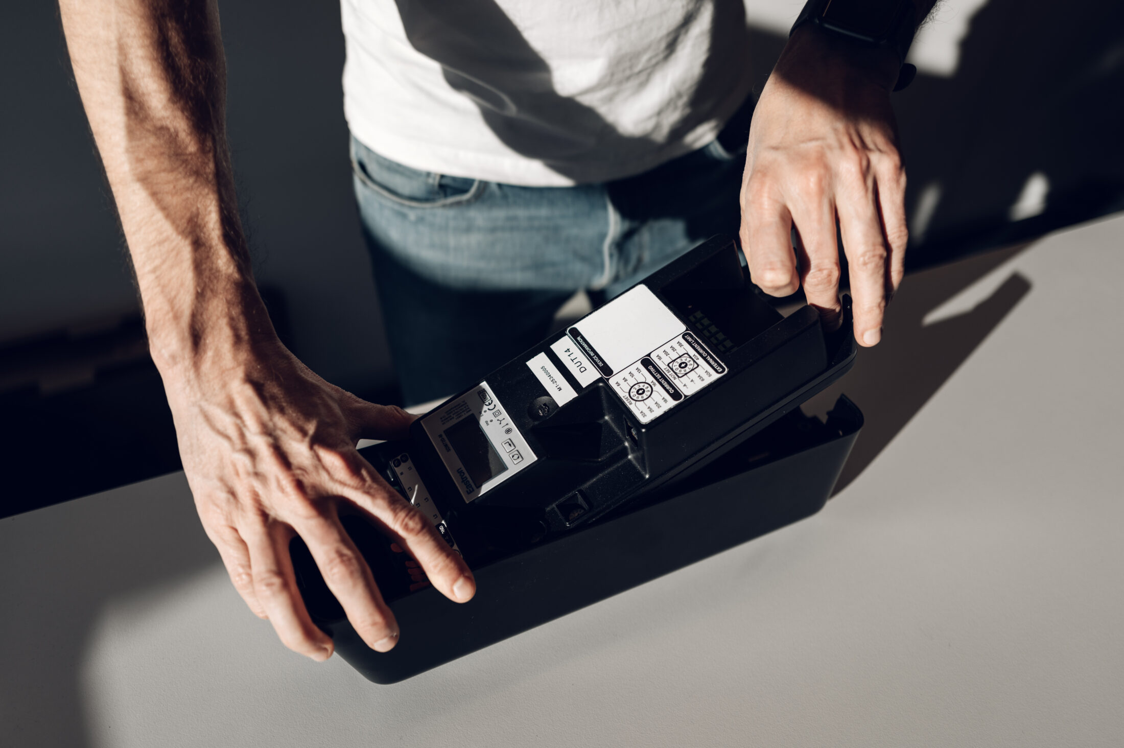 Hands holding black amina charger showing cable connections and connectors
