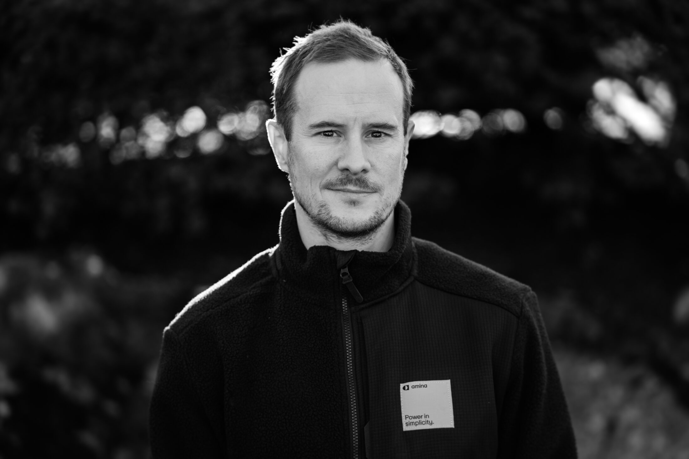 Person wearing black amina charger jacket with product badge visible